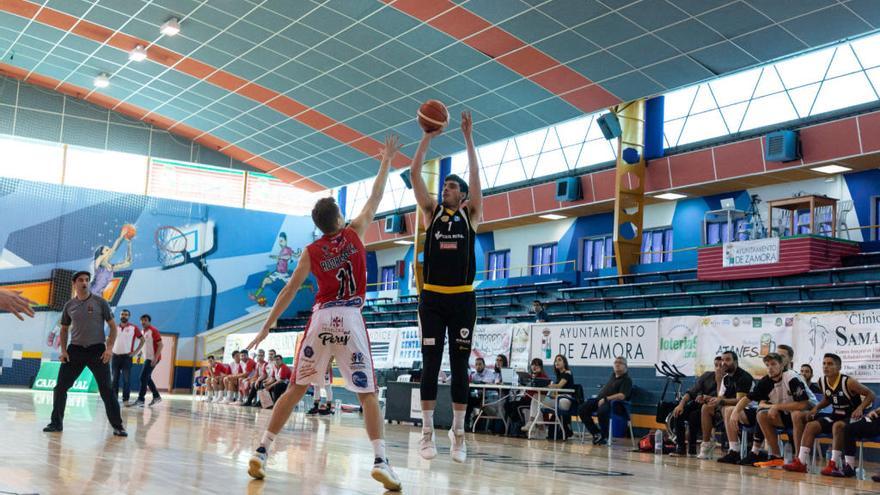 Juanma Robles lanza desde la línea de tres defendido por un jugador del Gijón Basket