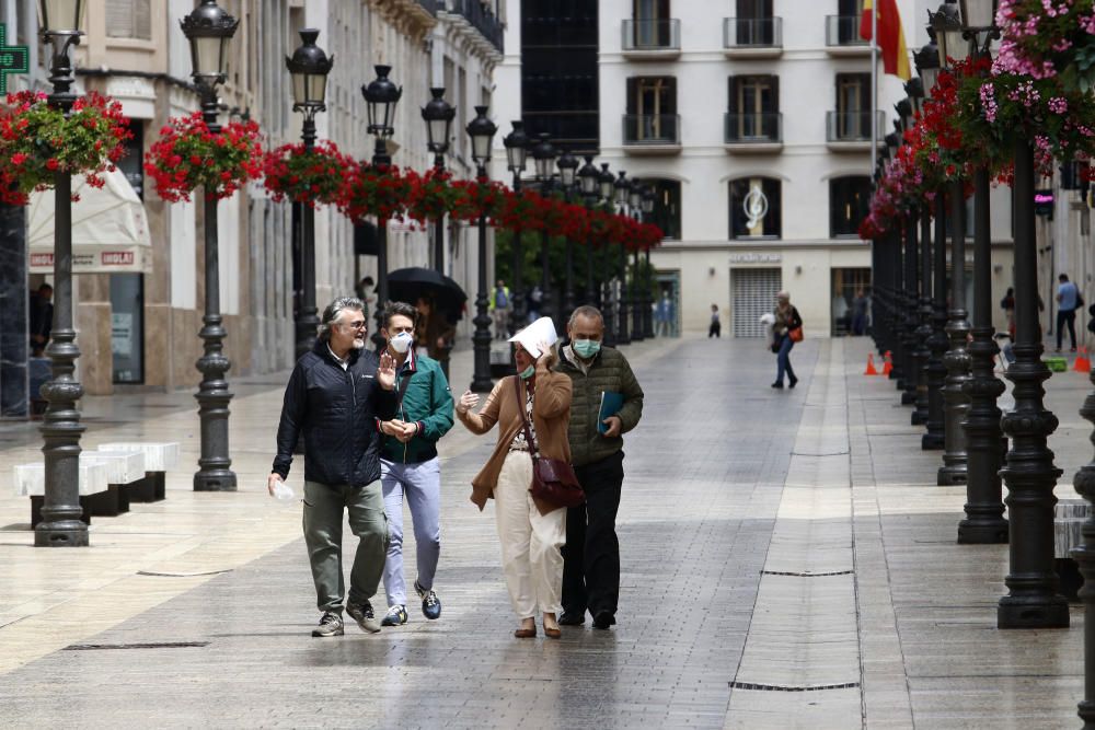 Imágenes de una lluviosa mañana de jueves en el centro de Málaga, donde al paisaje ya habitual de pocas personas y la mayoría de ellas con guantes y mascarillas se le han añadido los preparativos de bares, cafeterías y terrazas que se preparan para el inminente cambio de fase de la desescalada de la ciudad.