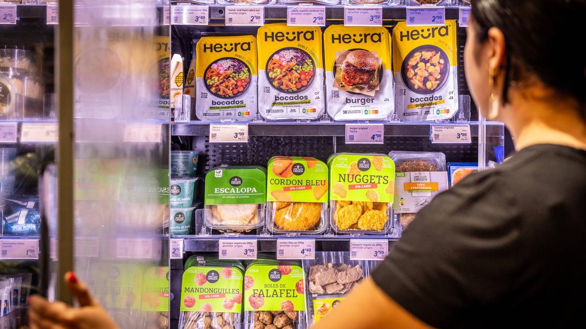 Una mujer acude a un estante del supermercado en el que se venden diferentes productos de proteína vegetal.