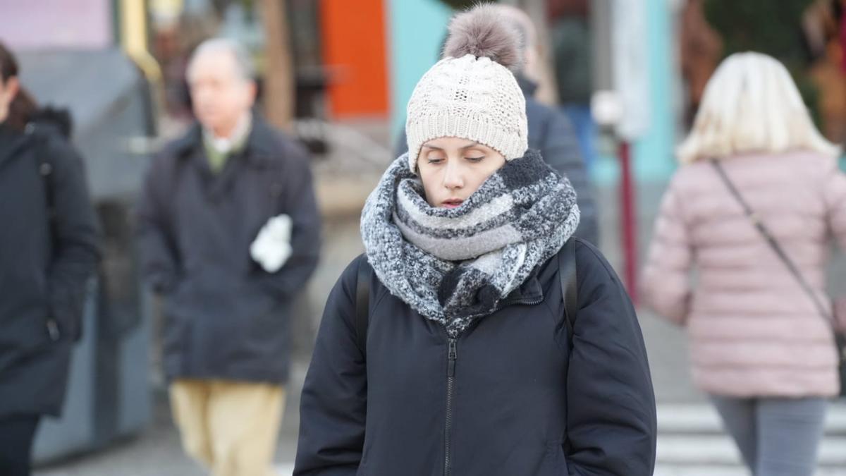 Una mujer camina por Córdoba bien abrigada contra el frío este jueves.