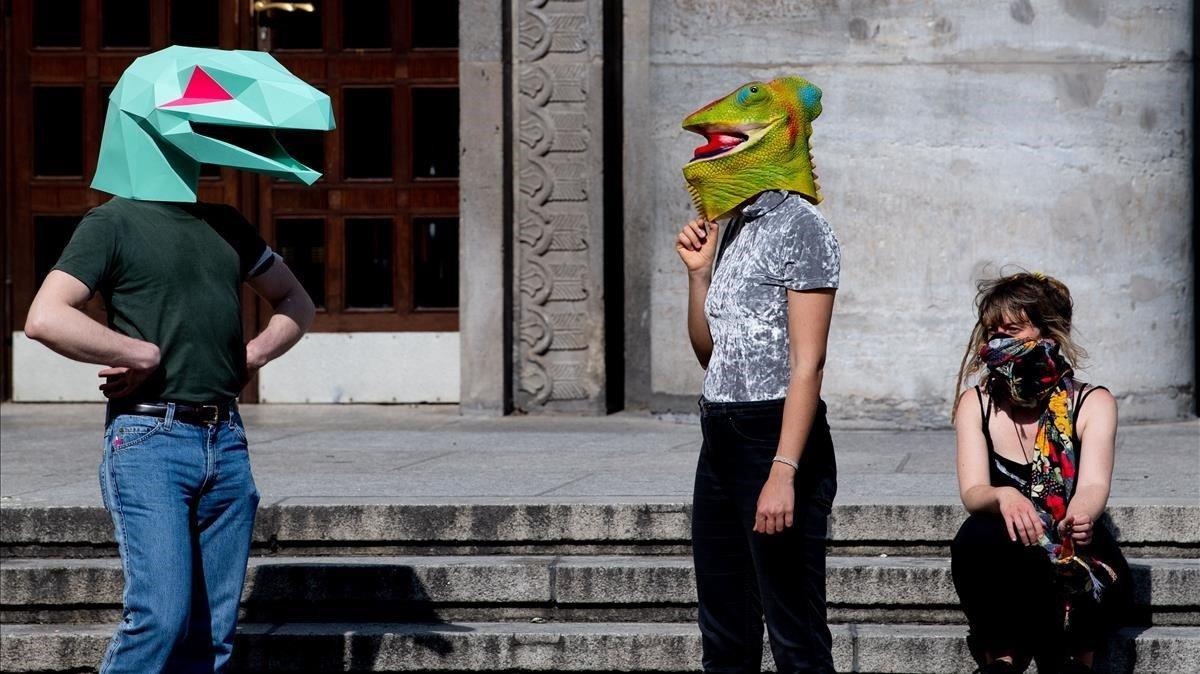 Manifestantes con mácaras de reptiles durante una protesta contra las restricciones y medidas implementadas para detener la propagación del coronavirus