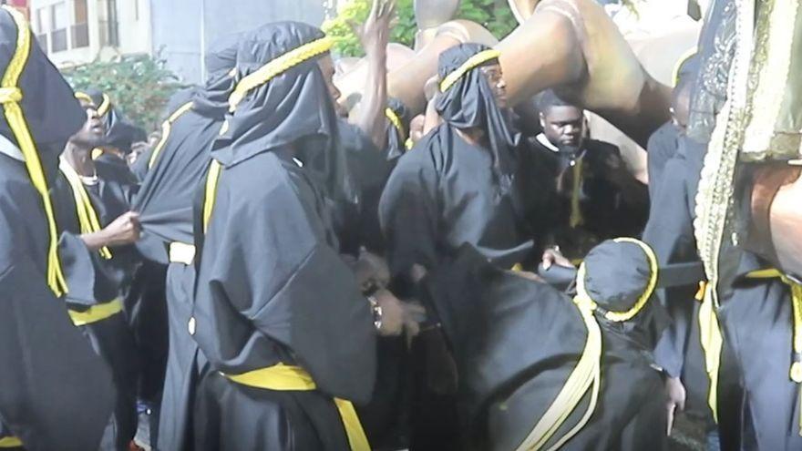 Los hombres subsaharianos que portan al embajador blanco discuten en mitad del desfile de Moros y Cristianos de Orihuela