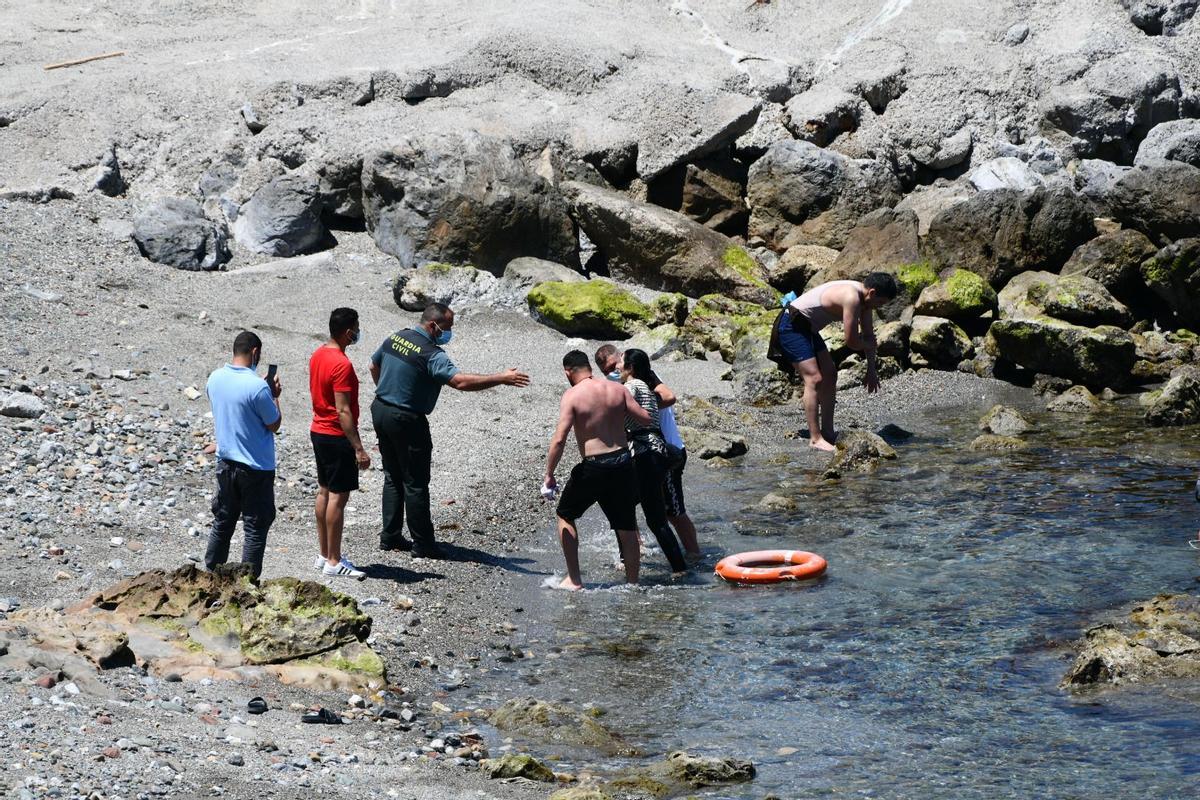 Miembros de la Guardia Civil ayudan a migrantes llegados a Ceuta en mayo.