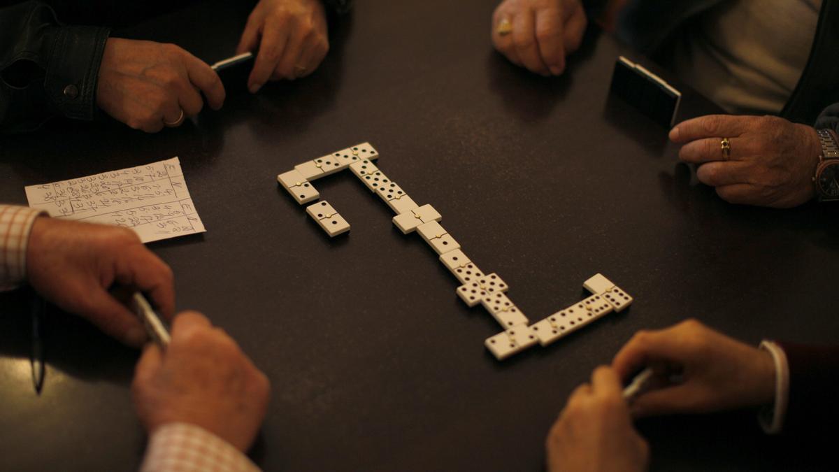 Un grupo de jubilados juega al dominó