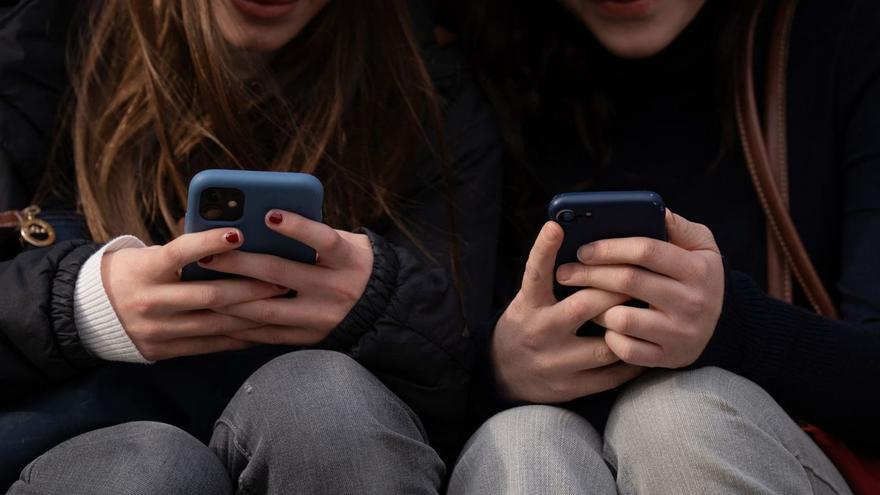 Dos adolescentes usando sus teléfonos.