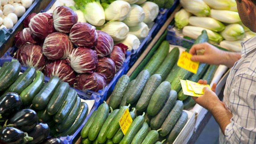 Un hombre, ante un puesto de frutas y verduras.