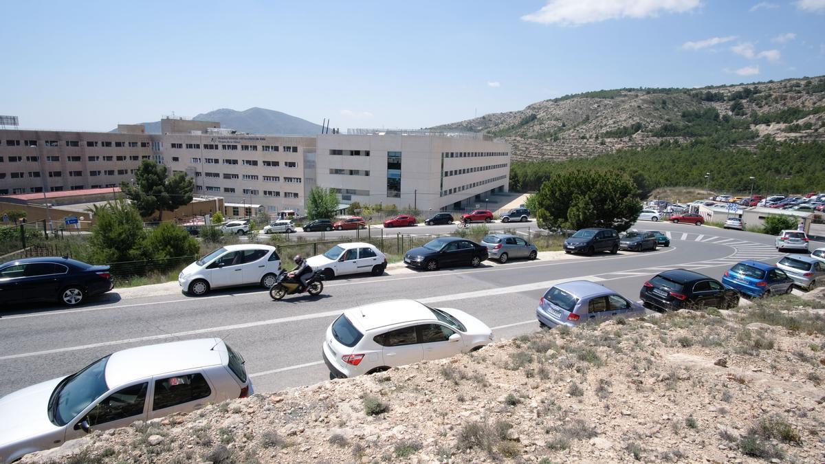 Vehículos aparcados en los arcenes de la carretera comarcal de La Torreta donde se encuentra el Hospital de Elda.