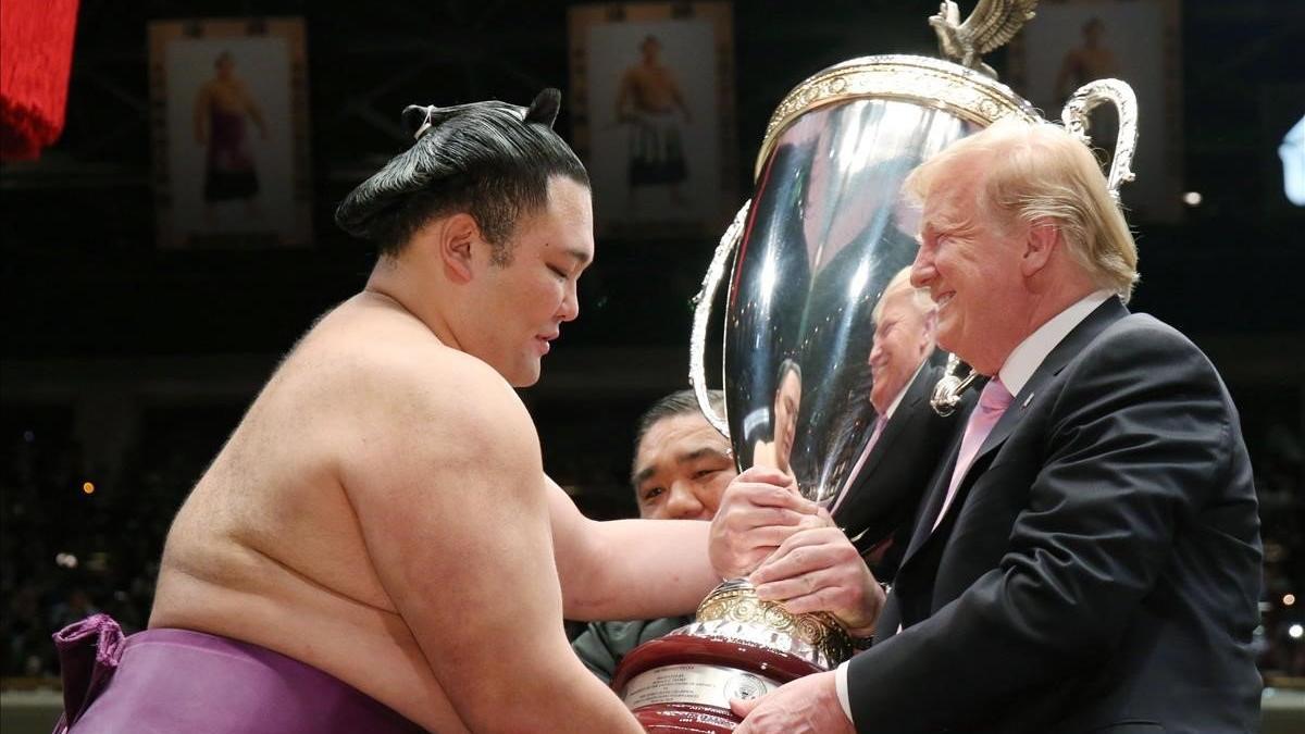 Trump recibe una copa de parte de un luchador de sumo, este domingo en Tokio.