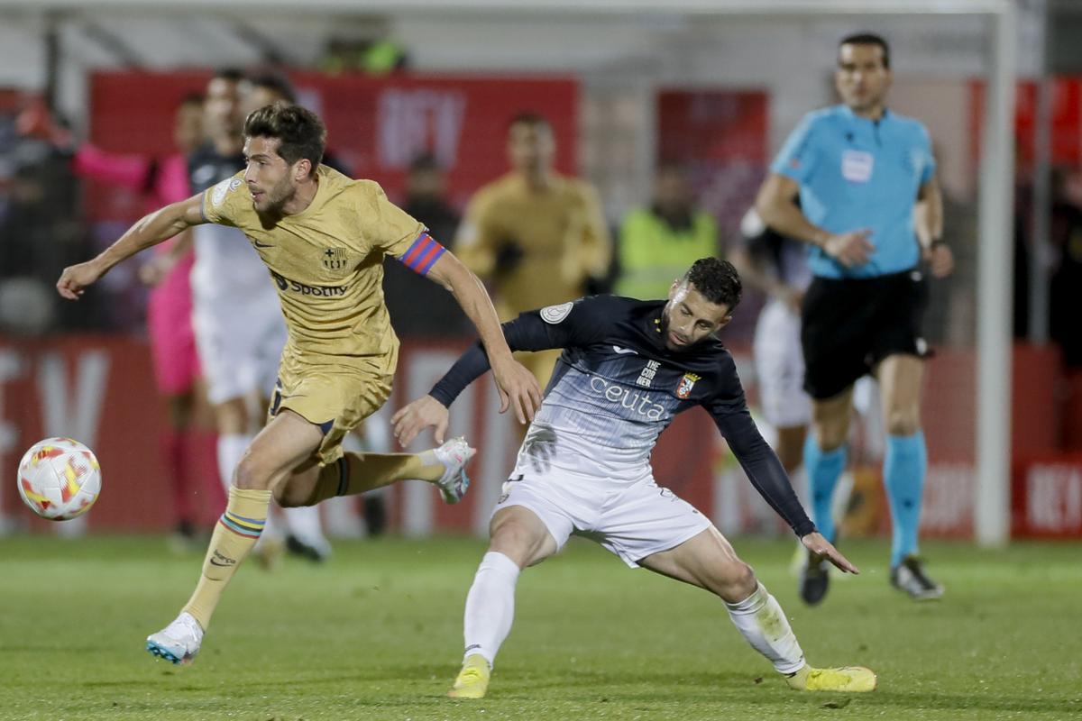 CEUTA, 19/01/2023.- El centrocampista del FC Barcelona Sergi Roberto (i) escapa de Rodri Ríos, del Ceuta, durante el partido de octavos de final de Copa del Rey que AD Ceuta y FC Barcelona disputan este jueves en el estadio Alfonso Murube de la ciudad autónoma de Ceuta. EFE/José Manuel Vidal