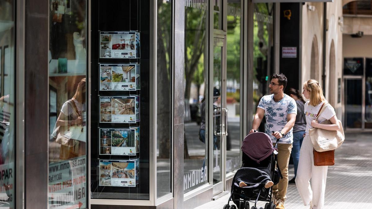 Dues persones davant l'aparador d'una immobiliària, en una imatge d'arxiu.