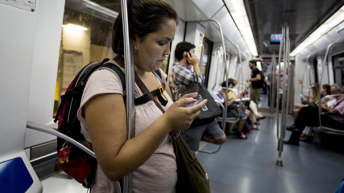 Una viajera del metro de Barcelona consulta su teléfono móvil
