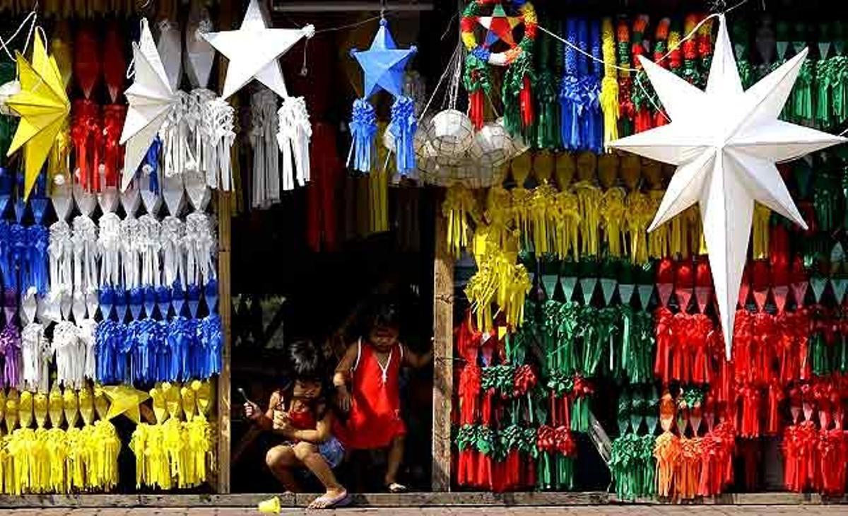 Dues nenes filipines juguen a l’entrada a una botiga de llums de Nadal en un suburbi de Manila (Filipines).
