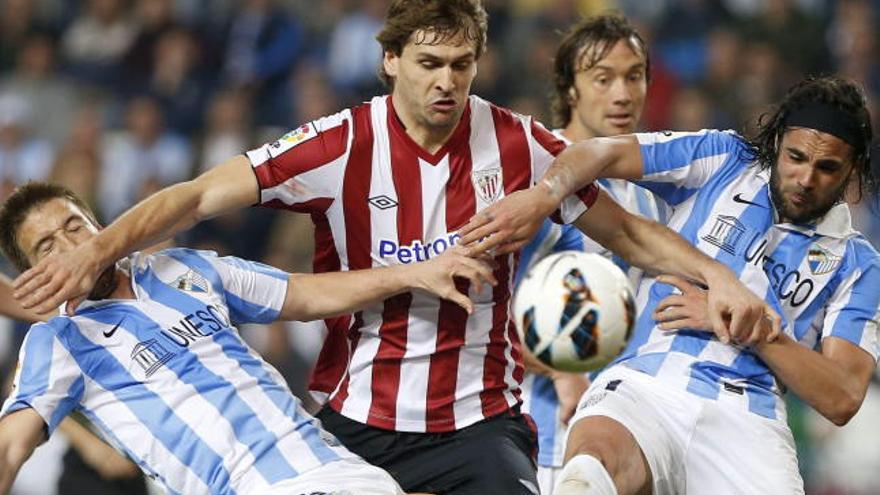 Llorentelucha el balón ante los jugadores del Málaga Sergio Sánchez y Camacho.