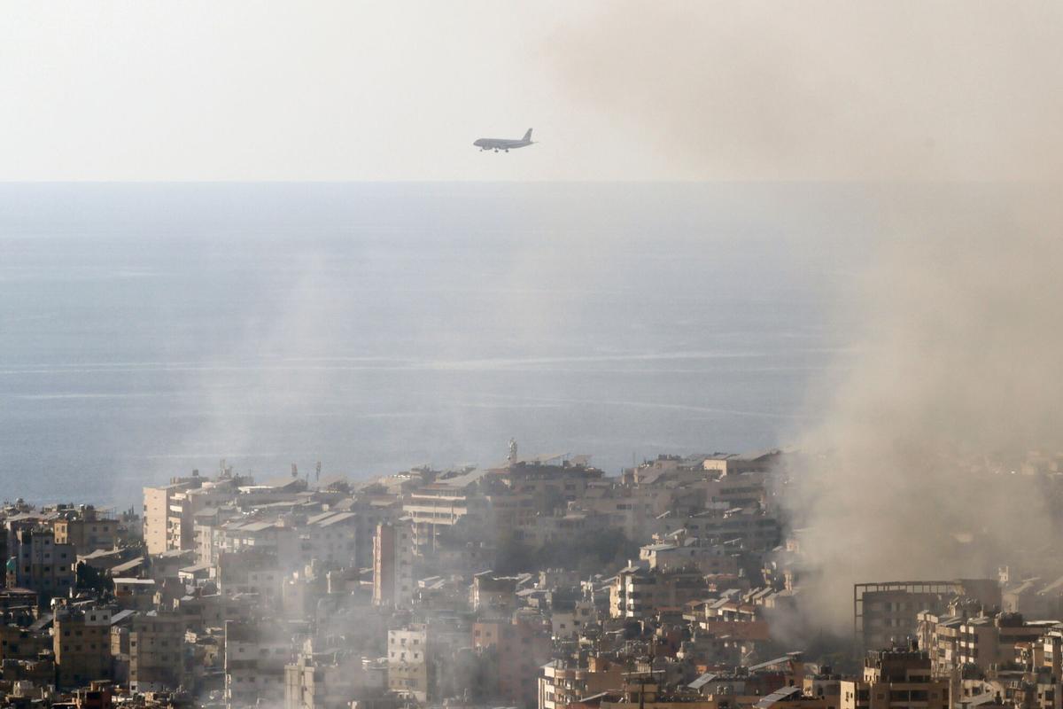Un avión de Middle East Airlines se prepara para aterrizar en el Aeropuerto Internacional de Beirut, mientras columnas de humo provocadas por bombardeos israelíes se elevan al cielo.