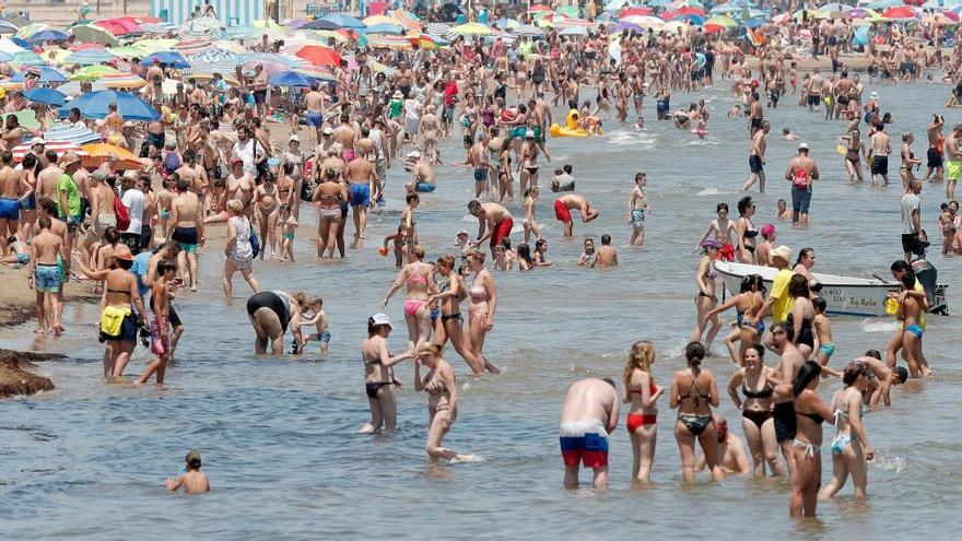 Un gran número de personas se refresca en las aguas de la playa de la Malvarrosa.