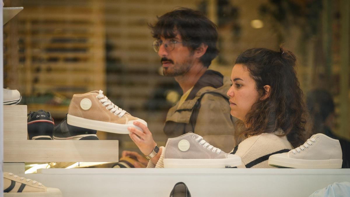 Una pareja mira la oferta de tenis de una tienda de las Islas.