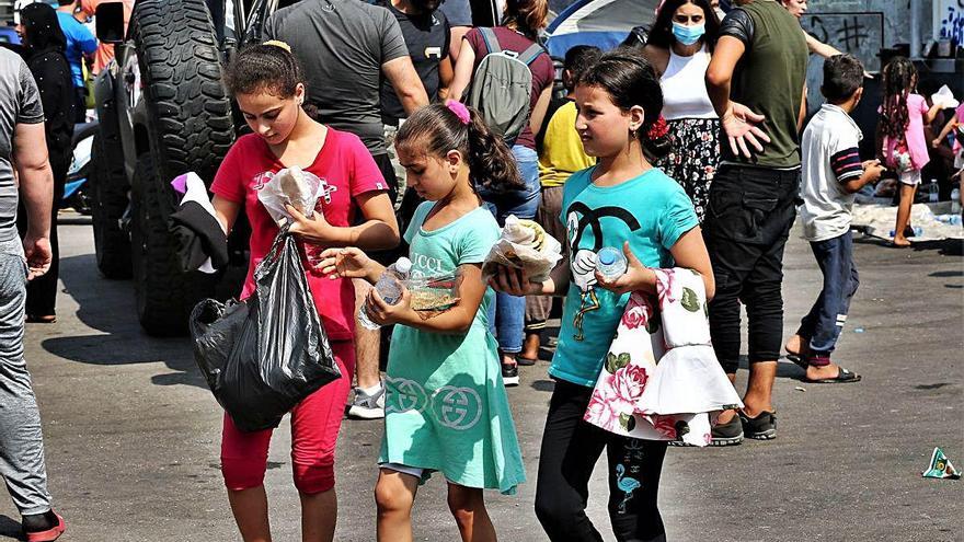 Tres nenes s&#039;emporten bosses amb ajuda humanitària.