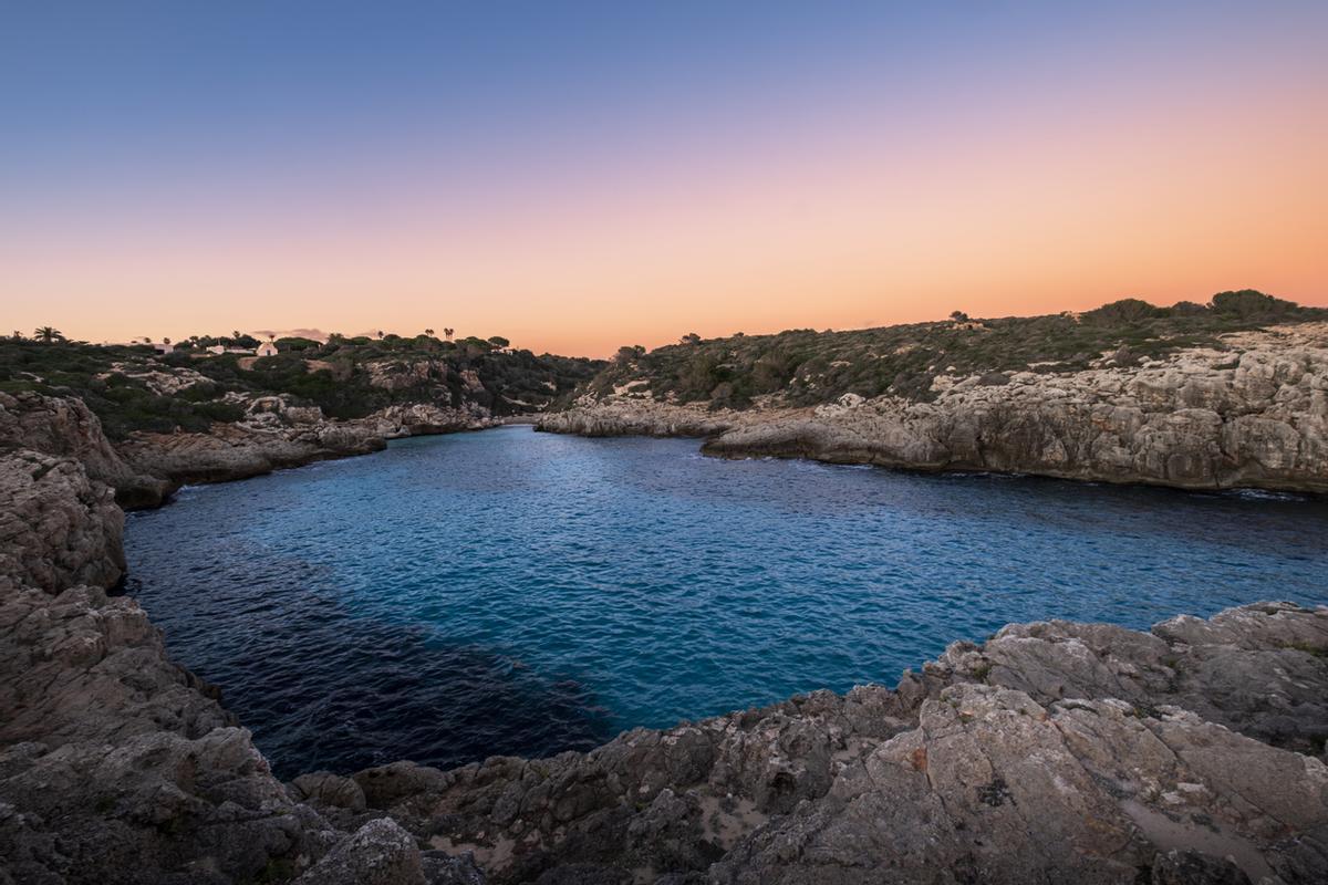 La tranquila cala, los acantilados rocosos y las últimas luces del atardecer