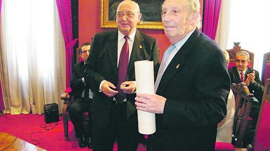 Humberto Alonso, a la derecha, recibe el título de manos del alcalde de Villaviciosa, Manuel Busto.