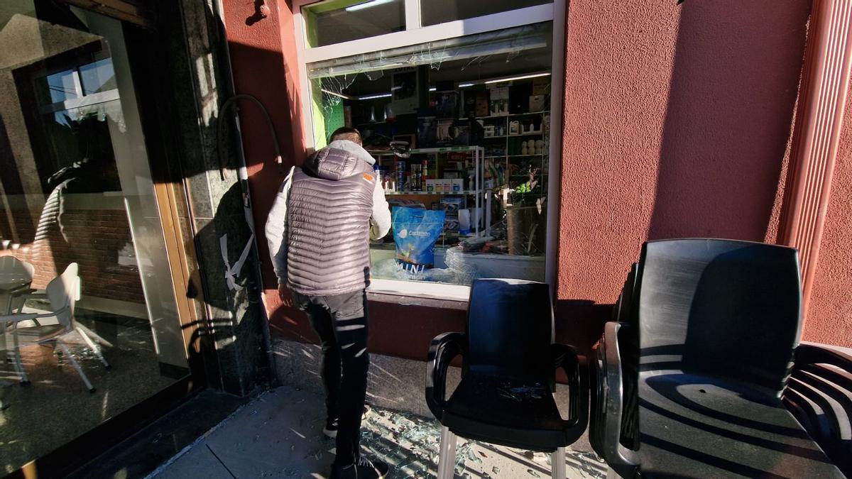 El dueño de la tienda junto a la ventana por la que entraron los ladrones.