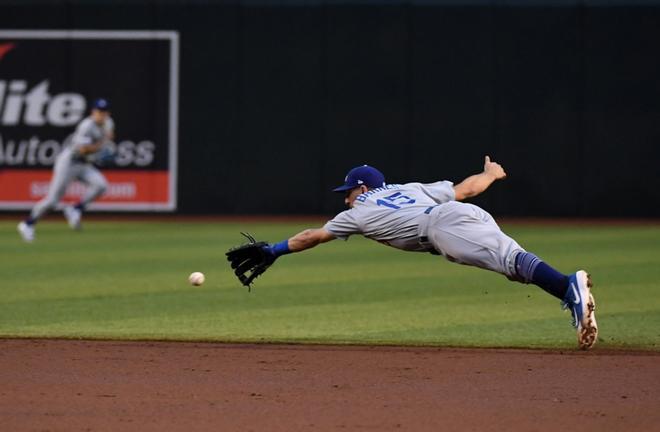 Austin Barnes # 15 de Los Angeles Dodgers no puede hacer una parada de buceo en un RBI single de David Peralta # 6 de los Arizona Diamondbacks durante la tercera entrada en el Chase Field, en Phoenix, Arizona.