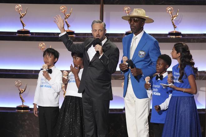 Host Nate Bargatze, left, JB Smoove and children from the Girls and Boys Club appear on stage during the 77th Primetime Emmy Awards on Sunday, Sept. 14, 2025, at the Peacock Theater in Los Angeles. (AP Photo/Chris Pizzello). 091425132020, 21334631,