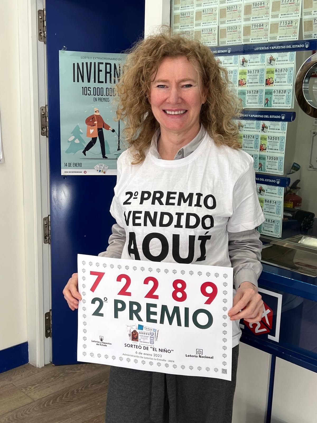 La responsable del despacho de lotería de Guillena muestra el cartel con el número del segundo premio del sorteo del Niño.