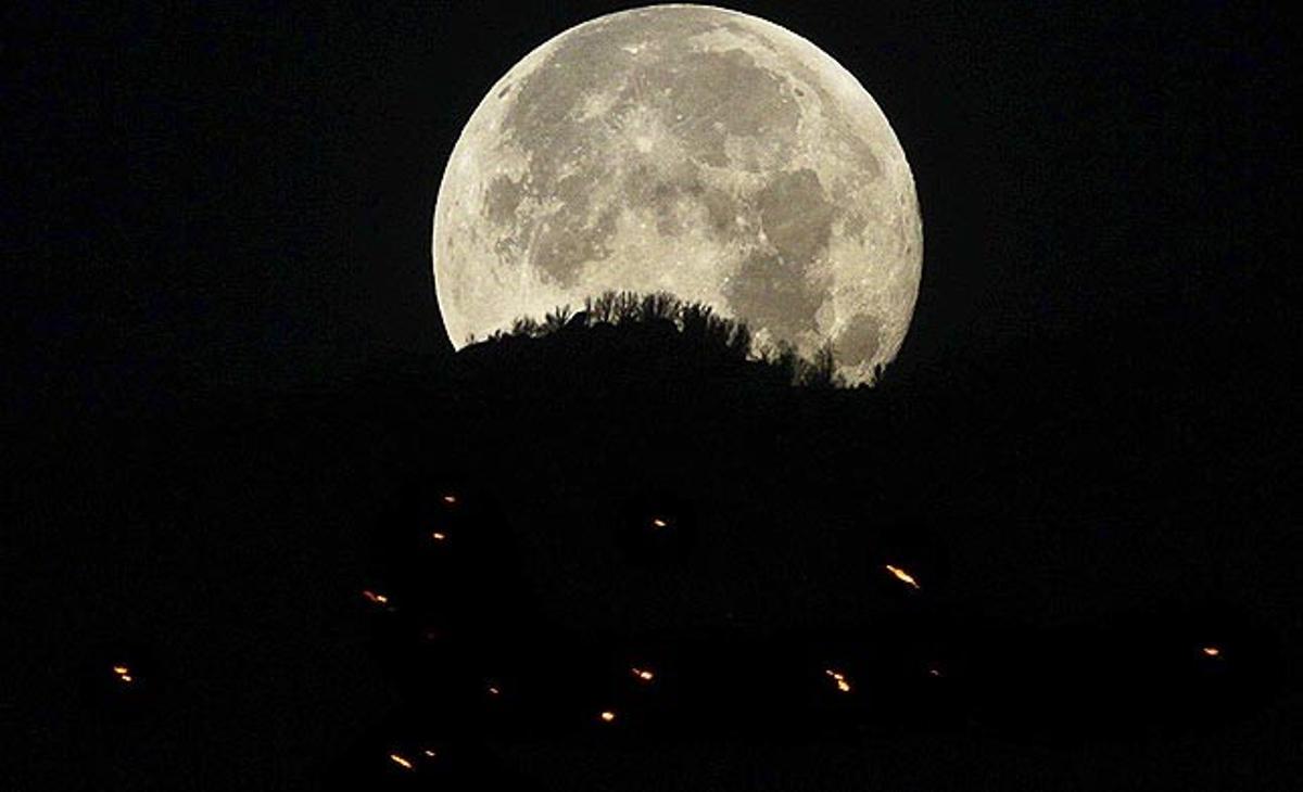 La Lluna es pon aquest dijous darrere una muntanya pròxima a la ciutat de Hereford (Estats Units). Els incendis forestals que s’estan produint en diversos punts del sud de l’estat d’Arizona encara no han estat extingits i es calcula que només al Bosc Nacional Coronado fins a 40 cases han estat destruïdes pel foc.