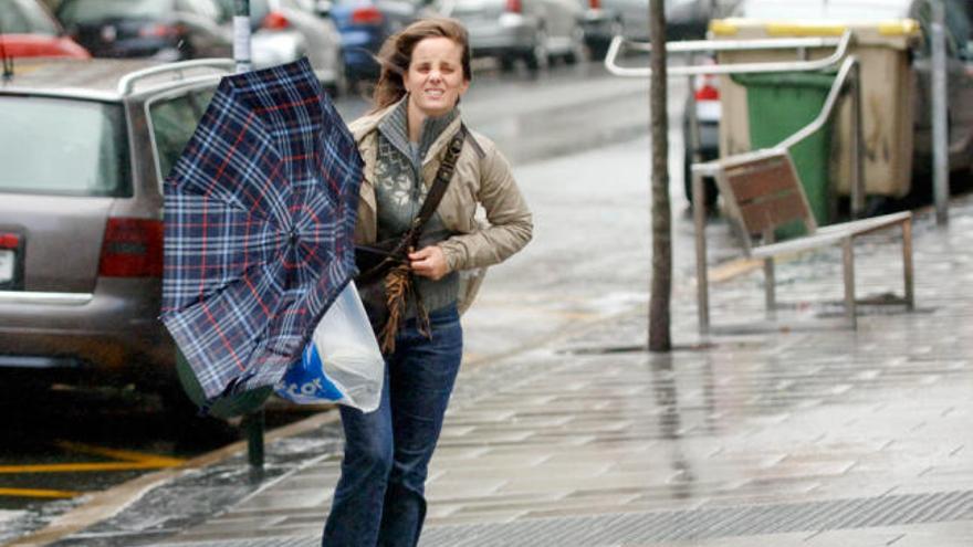 Una chica intenta protegerse de la lluvia y del viento. / Fran Martínez