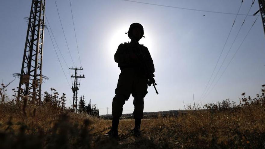 Un soldado israelí vigila a unos protestantes palestinos.