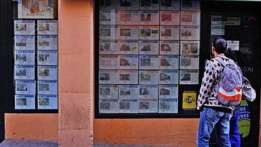 Un hombre observa los carteles de una agencia inmobiliaria.