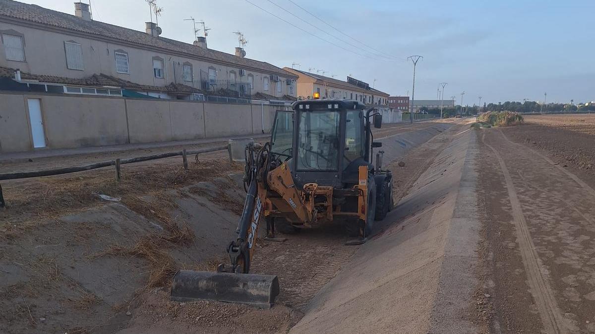 Una máquina retira restos de maleza y tierra de un canal ubicado en Los Alcázares.
