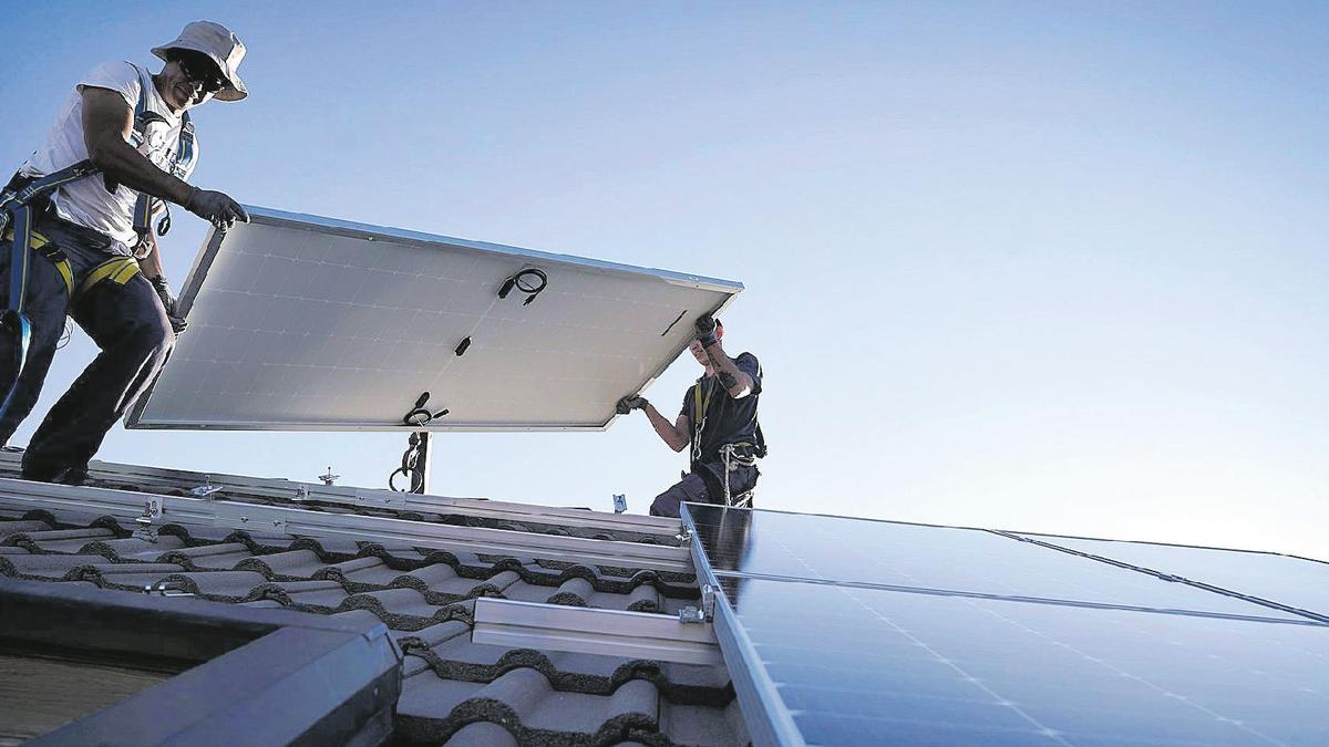 Tècnics instal·lant plaques solars a la teulada d'un habitatge