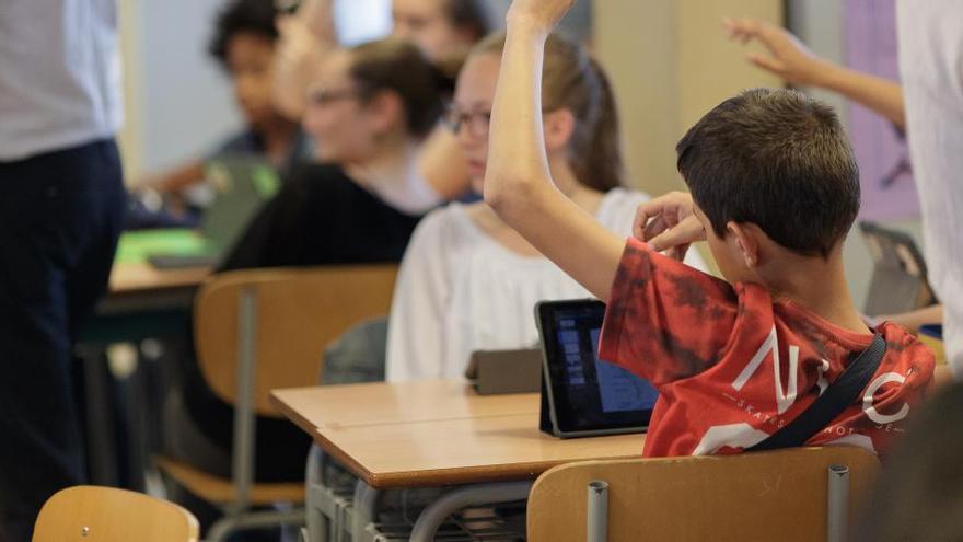 Un alumno levanta la mano durante una clase con dispositivos digitales, imagen de archivo.