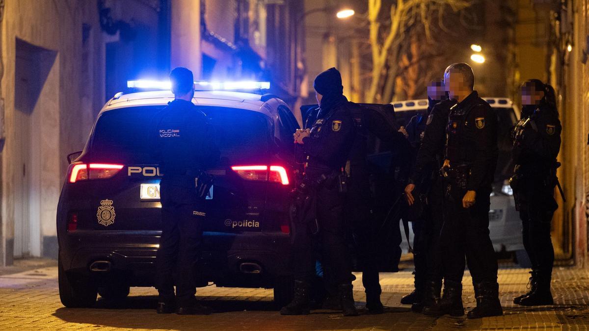 Momento en el que la Policía traslada a dos de los detenidos a dependencias policiales, este viernes por la noche en la calle Montañés de Zaragoza.