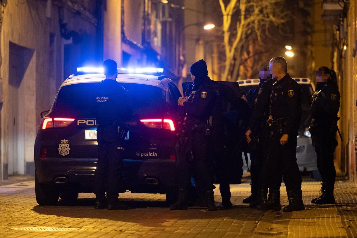 Momento en el que la Policía traslada a dos de los detenidos a dependencias policiales, este viernes por la noche en la calle Montañés de Zaragoza.