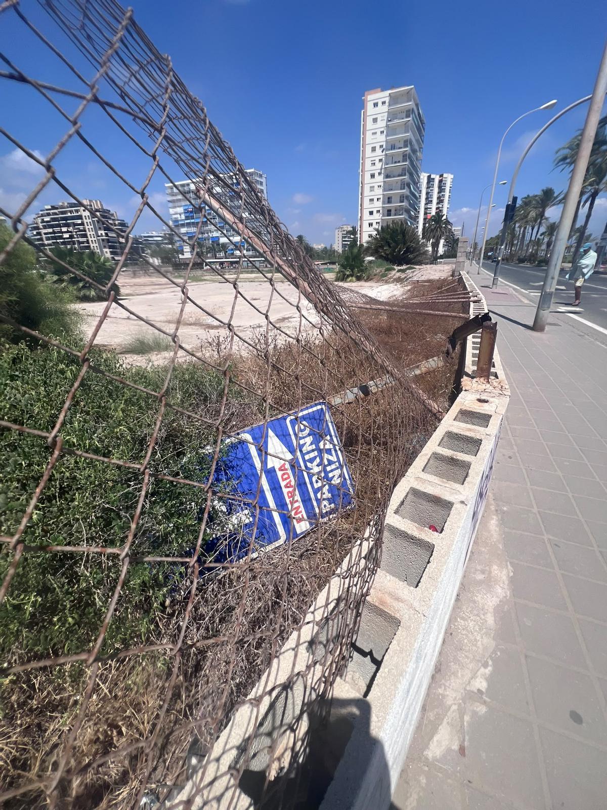 Estado del vallado situado frente a la playa de San Juan, con malla deteriorada, vegetación seca y restos acumulados.