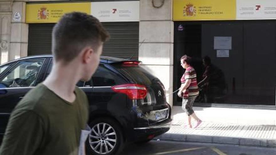 Dos viandantes pasan por delante de la sede de la Seguridad Social en Alzira.
