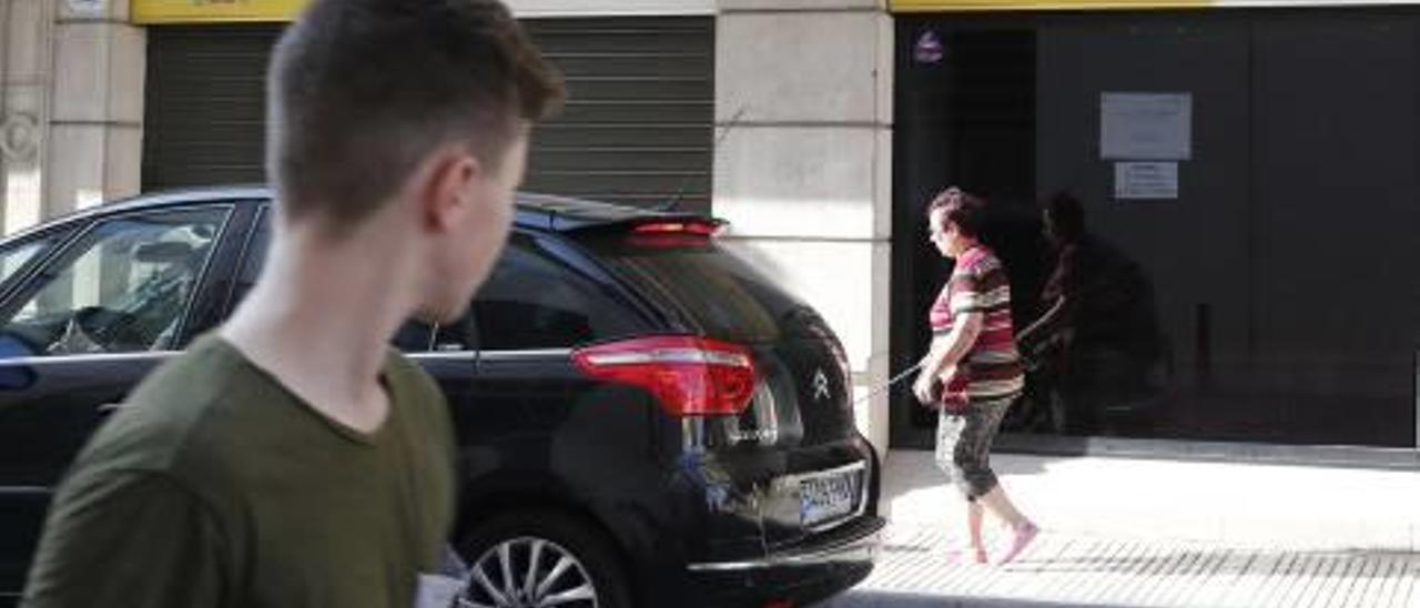 Dos viandantes pasan por delante de la sede de la Seguridad Social en Alzira.