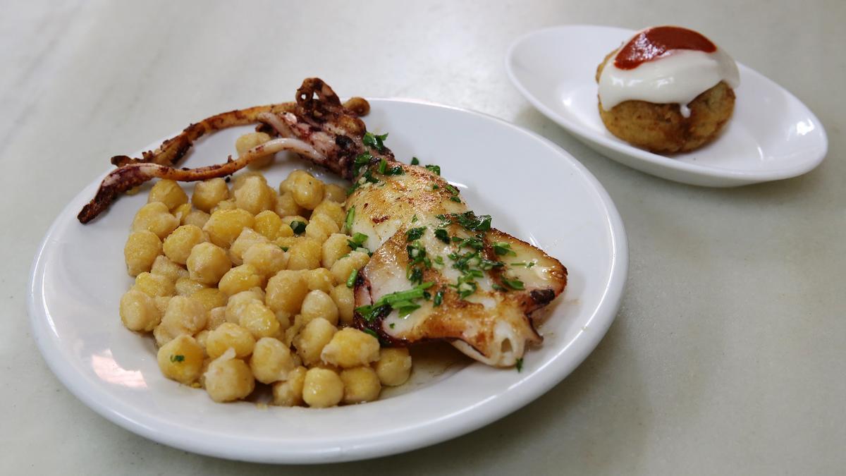 La bomba de la Cova Fumada junto a un plato de garbanzos y calamar.