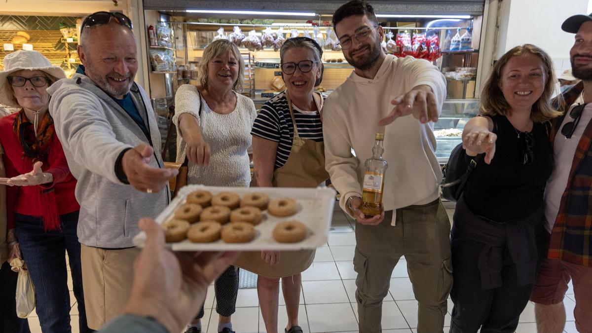 Un grupo de turistas prueba los dulces típicos de Santa Faz en una panadería de Alicante.