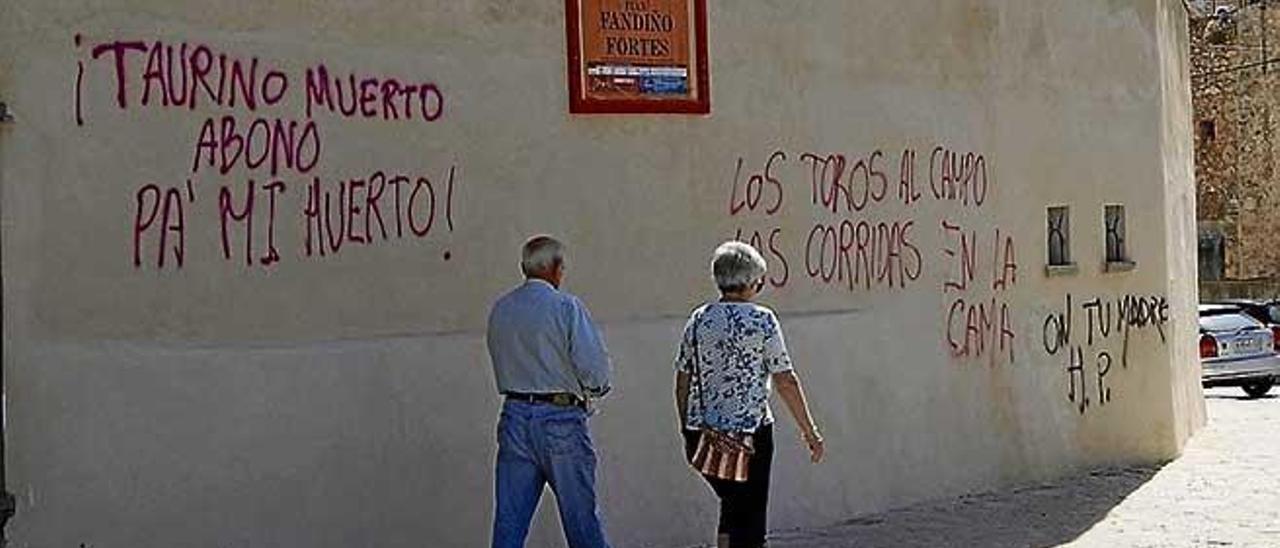 Dos transeúntes pasan ante las pintadas.