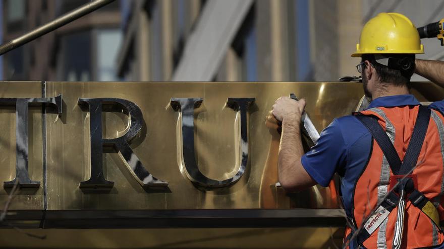 Un trabajador retira las palabras &quot;Trump Place&quot; de un edificio en Nueva York.