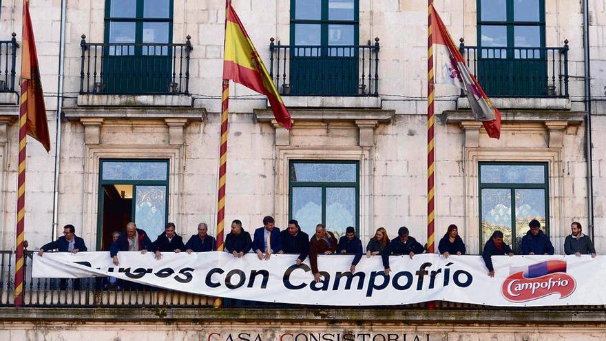 Representantes municipales y de los trabajadores colocan una pancarta en el balcón del Ayuntamiento de Burgos.