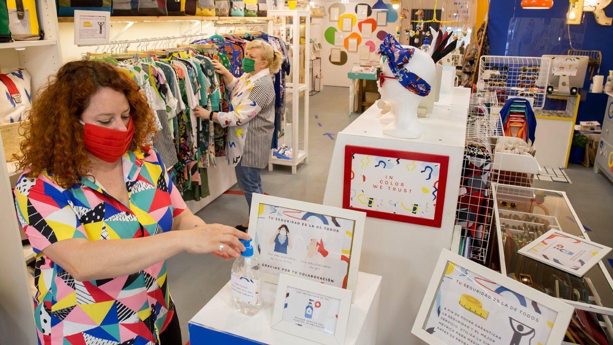 Gel hidroalcohólico y carteles con las medidas de prevención a la entrada de la tienda de moda local Rollito Así, en Gràcia