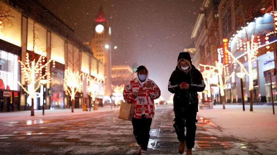 Dos personas con mascarillas por una calle vacía en Beijing. // Reuters