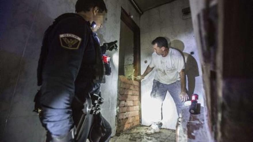 Un operario tapia la entrada al narcopiso en presencia de un policía local del GOIR.