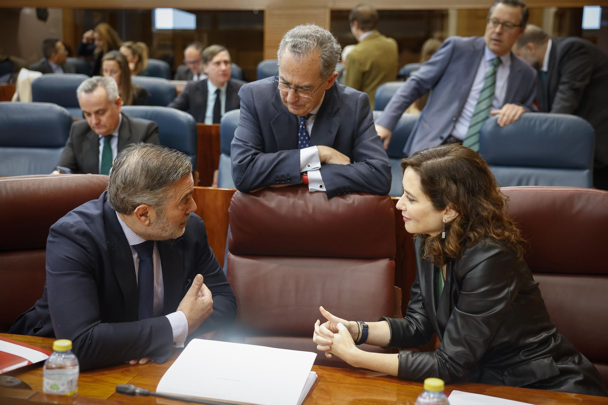 Isabel Díaz Ayuso habla con Enrique López en la Asamblea de Madrid ante la mirada de Enrique Ossorio