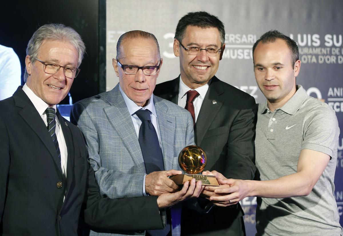 El exjugador barcelonista Luis Suárez (segundo por la izquierda), junto al presidente del FC Barcelona, Josep María Bartomeu,, y el jugador Andrés Iniesta, durante el acto de entrega esta tarde al Museo del FC Barcelona del Balón de Oro que alcanzó en 1960, cuando fue escogido mejor jugador de Europa. 