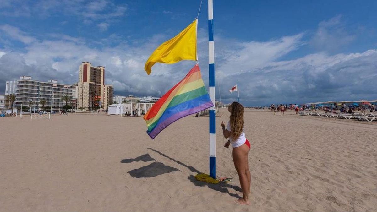 Una socorrista iza
la bandera LGTBI
en la playa de Gandia. Àlex Oltra